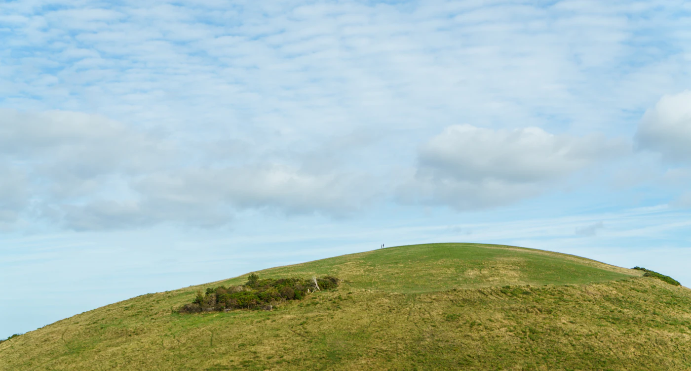 A green hill on the South Downs under a wide blue sky